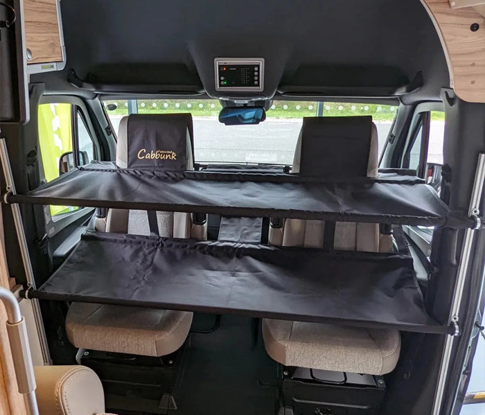 Camper van interior with folded black bed and 'Cabin bunk' branding.